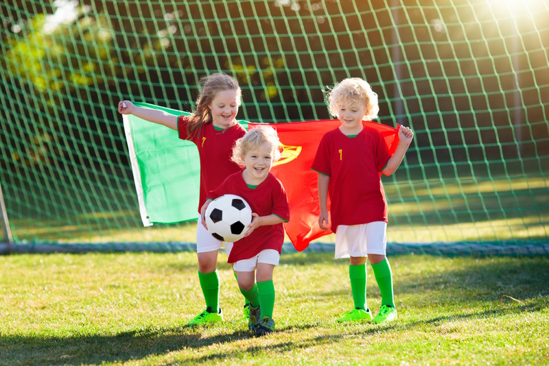 Kids play football on outdoor field.